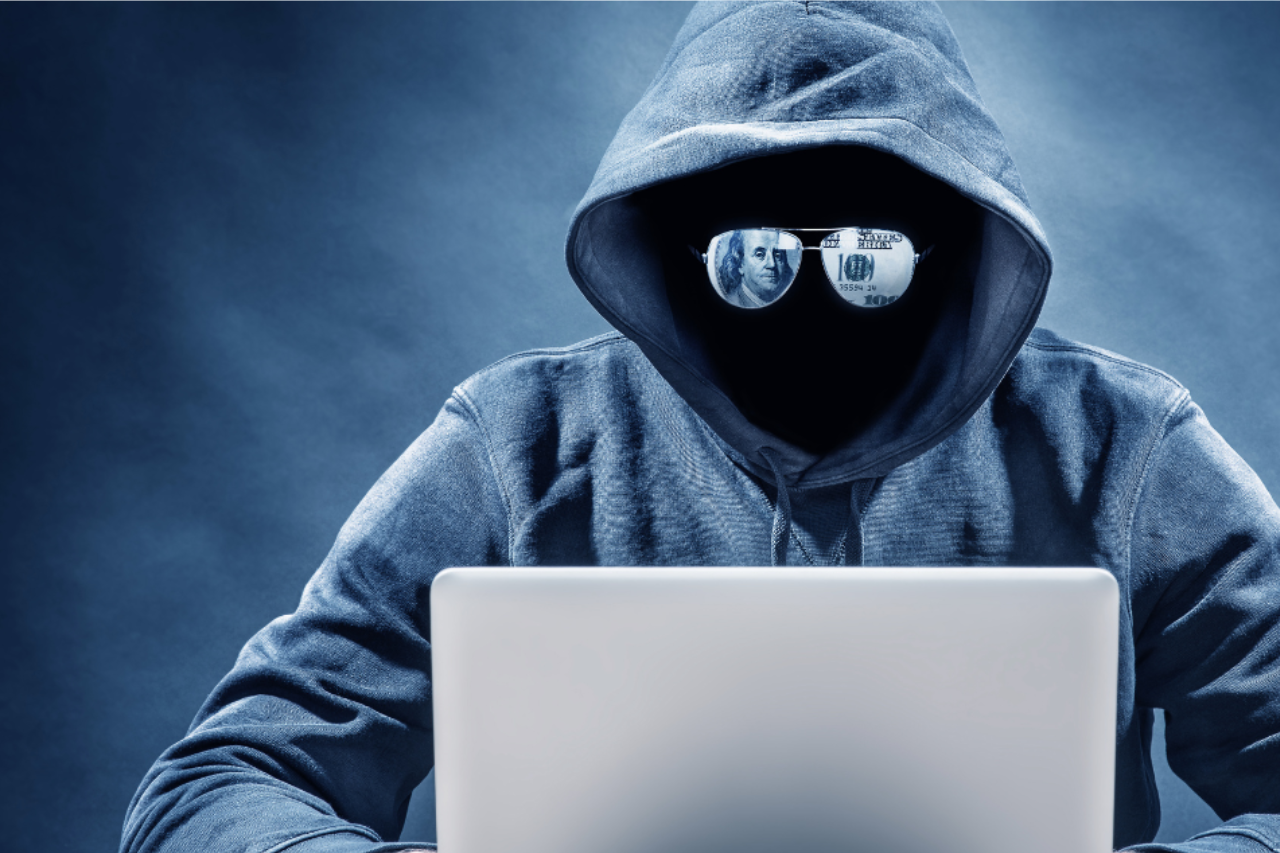 Preventing Fraud Man with sunglasses and hoodie at a laptop